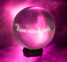Bola de cristal com fundo rosa, e o texto "esse não é caô".