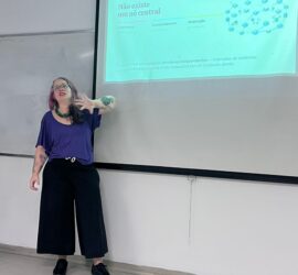 Mulher branca na frente de uma tela onde explico a ausência de um nó central nas redes federadas descentralizadas.